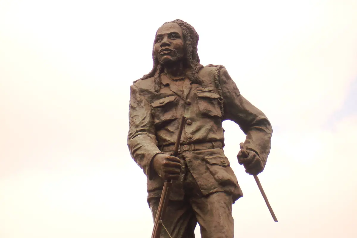 Bronzen standbeeld van Dedan Kimathi in veldkleding met een stok in zijn hand