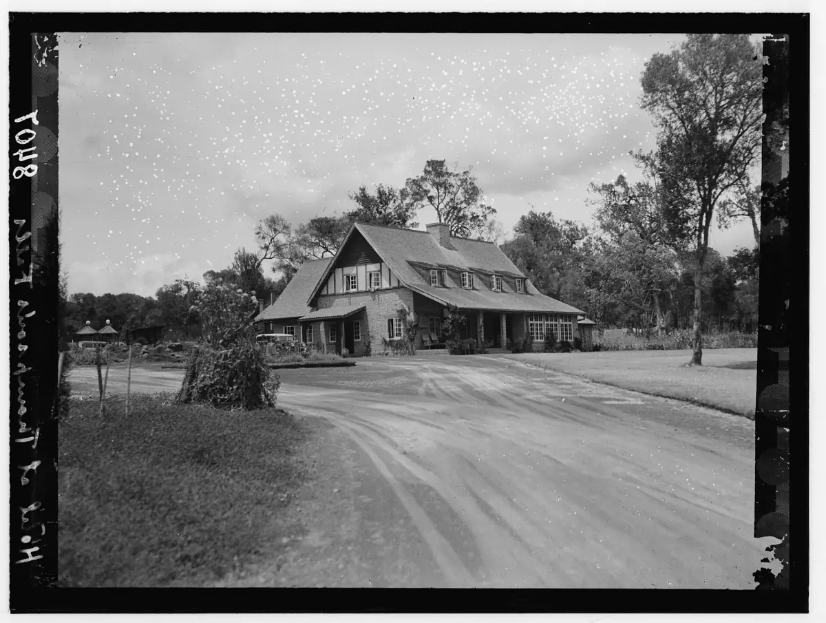 Historic black and white photo of a gabled lodge building with trees